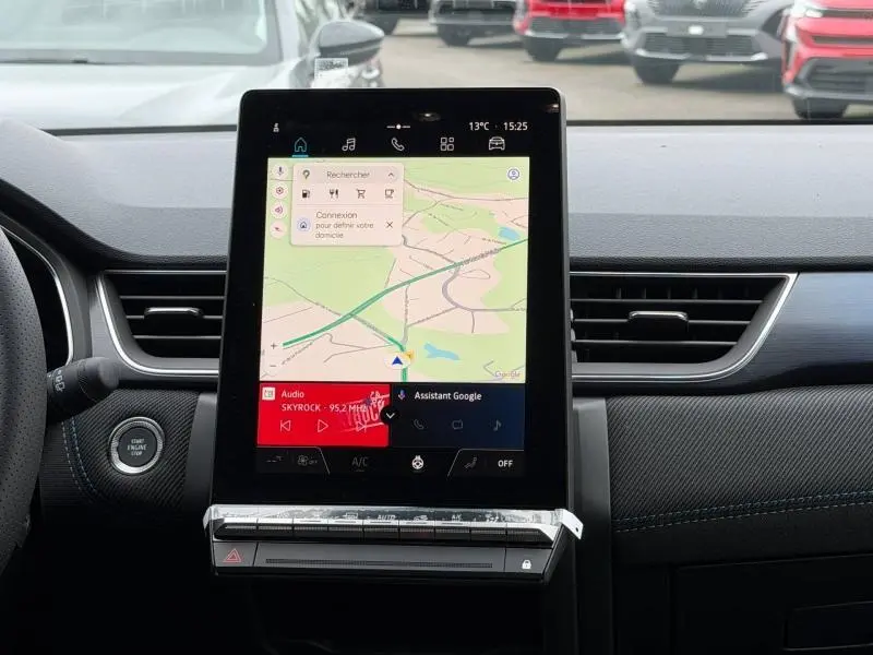 Vue intérieure centrée sur l'écran tactile vertical du tableau de bord du Renault Captur 2026, avec finition carbone et coutures bleues.