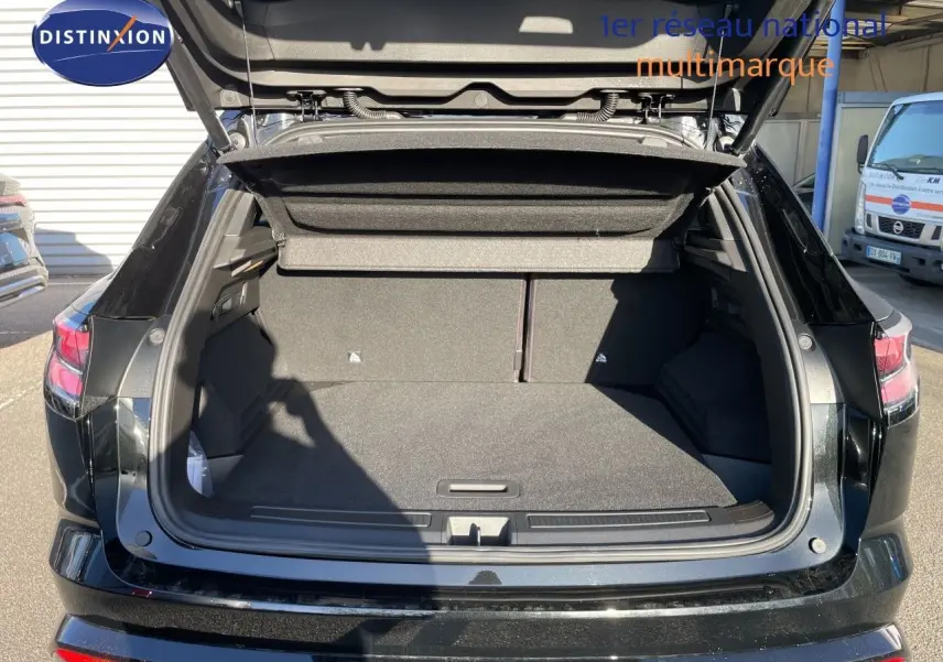 Coffre ouvert vu de l’arrière d’un Renault Austral noir étoile métal, montrant l’espace de chargement vide et la plage arrière relevée.