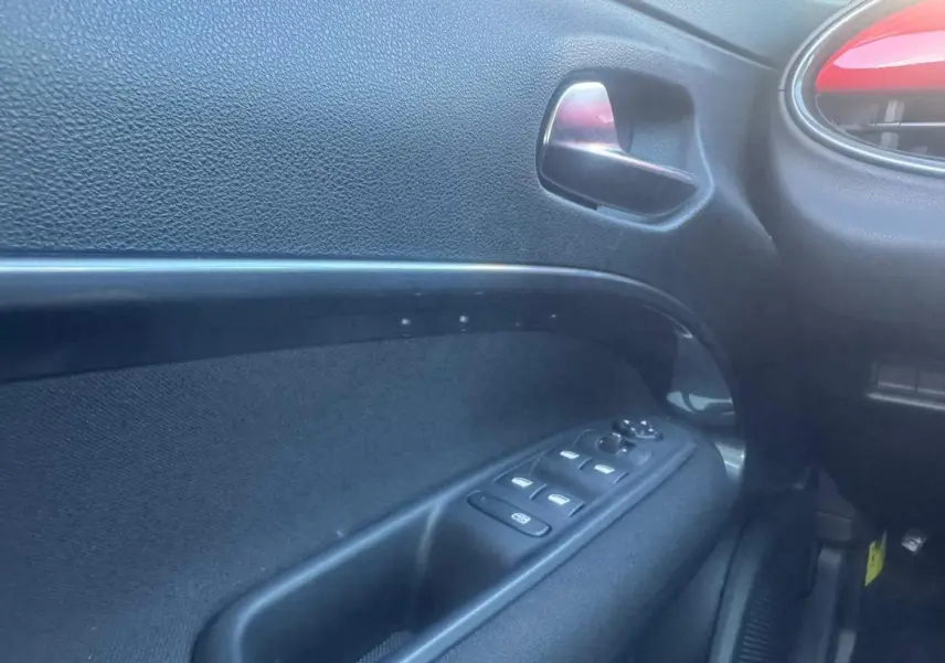 Intérieur côté gauche de la porte FIAT 600 T-Gen 3 rouge 2025, avec commandes de vitres et poignée métallique.
