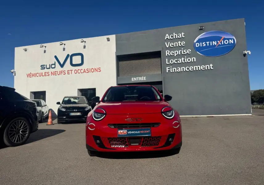Vue frontale d'une FIAT 600 T-Gen 3 rouge, avec ses phares ronds caractéristiques, stationnée devant un bâtiment commercial.