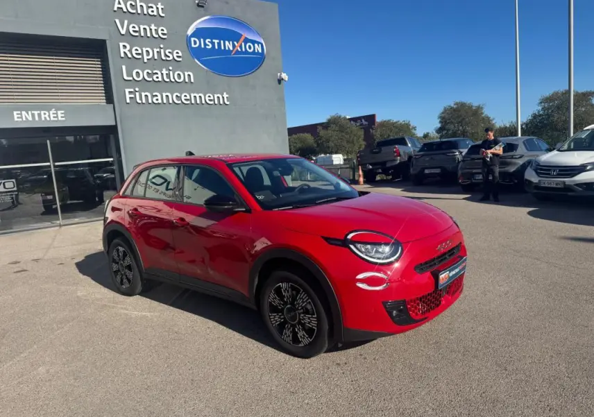 Vue 3/4 avant droite d'une FIAT 600 T-Gen 3 rouge brillante, avec jantes noires et détails modernes, devant un concessionnaire.