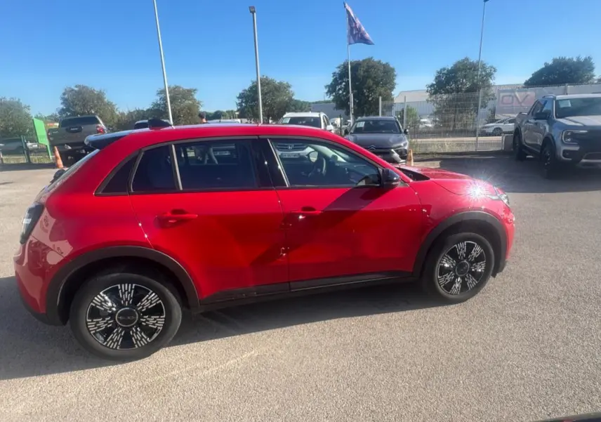 Vue de profil côté gauche d'une FIAT 600 T-Gen 3 rouge 2025 avec jantes noires au design graphique.
