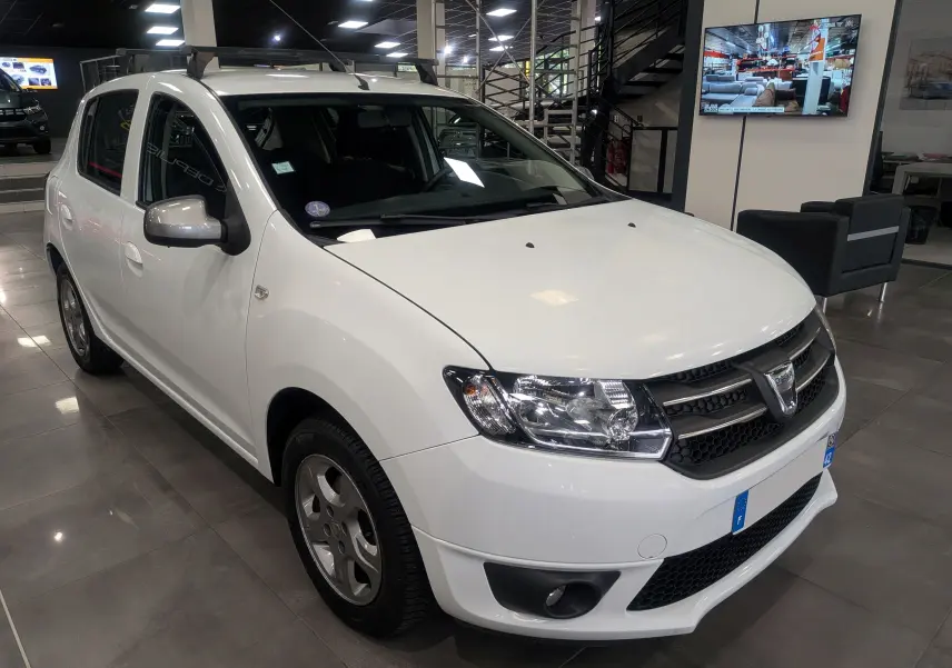 Vue 3/4 avant gauche d'une Dacia Sandero TCe 90 blanche Glacier, avec jantes alliage et calandre noire en showroom.