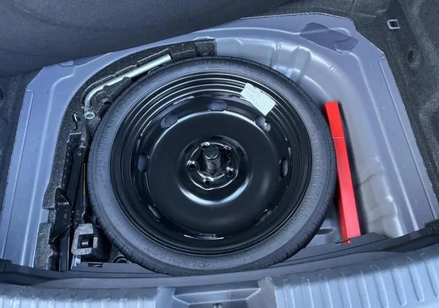 Vue plongeante sur la roue de secours noire dans le coffre d'une CUPRA Leon 2024 gris Graphene.