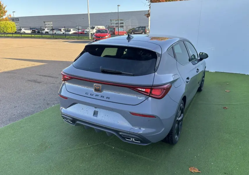 Vue 3/4 arrière droite d'une CUPRA Leon 2024 gris Graphene avec feux arrière LED et double sortie d'échappement.