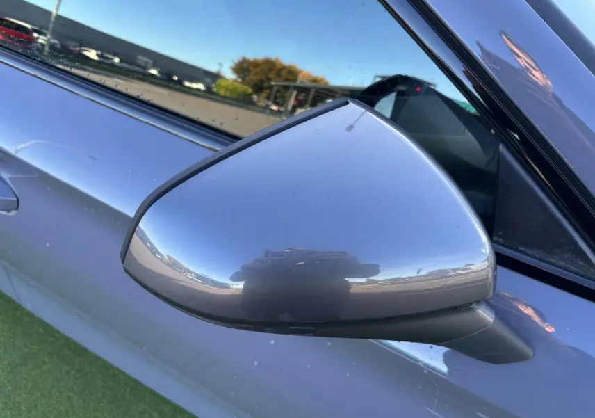 Rétroviseur côté gauche gris Graphene de la CUPRA Leon 2024, avec reflet et partie de la portière visible.