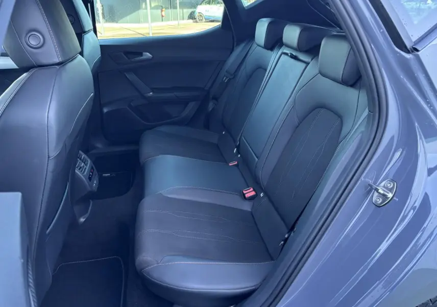 Vue intérieure côté droit des sièges arrière en cuir noir du CUPRA Leon 2024 gris Graphene, avec ceinture rouge visible.