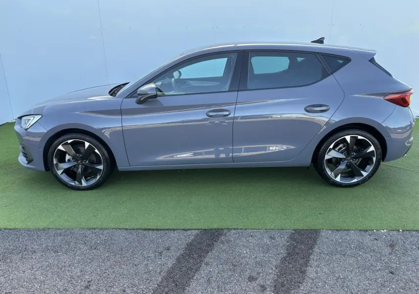 Profil droit d'une CUPRA Leon 2024 gris Graphene avec jantes alliage 18 pouces et vitres arrière surteintées.