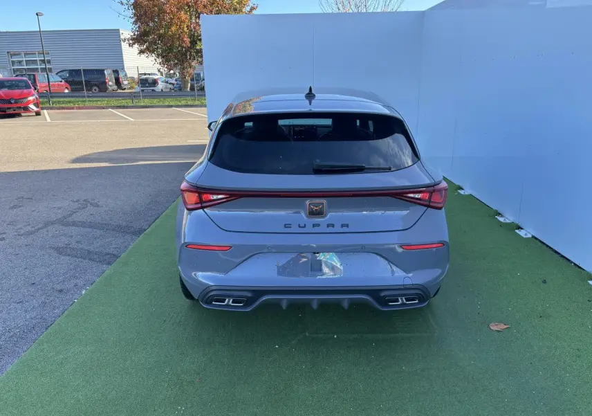 Vue arrière d'une CUPRA Leon 2024 gris Graphene avec feux LED reliés par un bandeau lumineux et double sortie d'échappement.