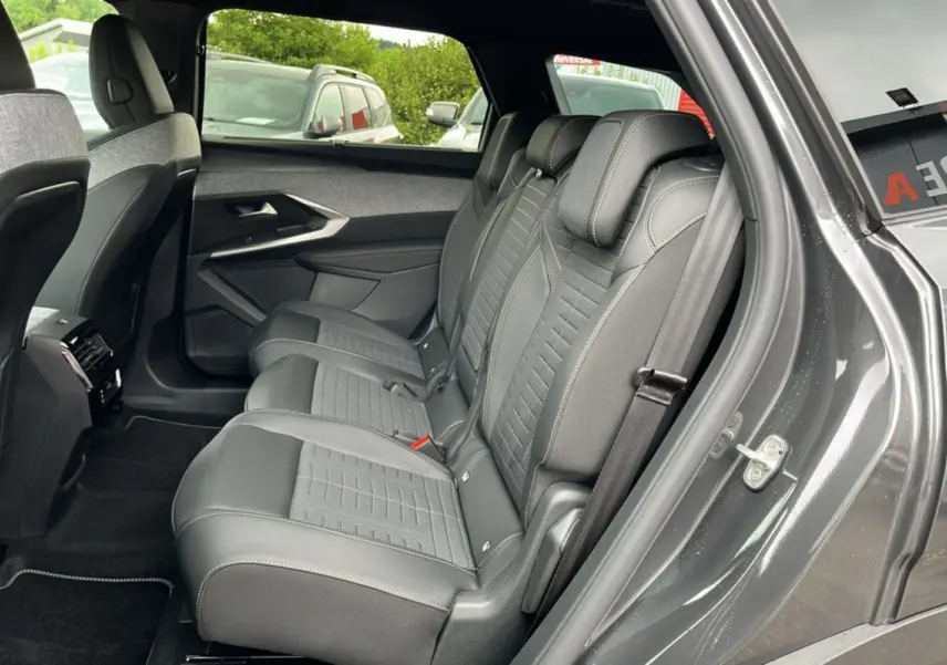Vue côté gauche sur la banquette arrière en cuir et tissu gris du Peugeot 5008 Hybrid 2025 gris titane avec toit noir.