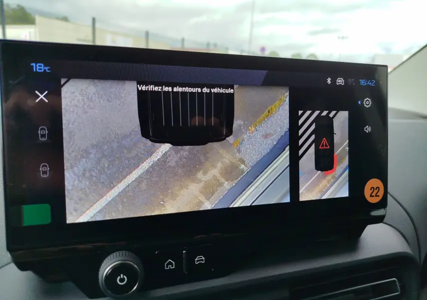 Écran intérieur du Peugeot Rifter noir Perla Nera montrant la caméra de recul avec vue aérienne du véhicule et avertissement.