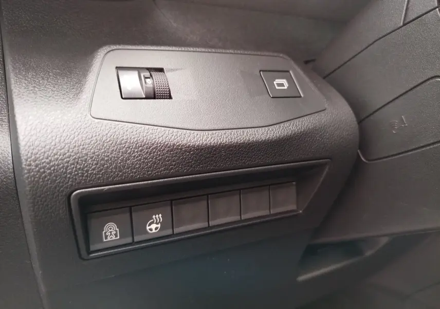 Détail intérieur côté gauche du tableau de bord noir du Peugeot Rifter 2026 avec commandes de verrouillage et chauffage volant.