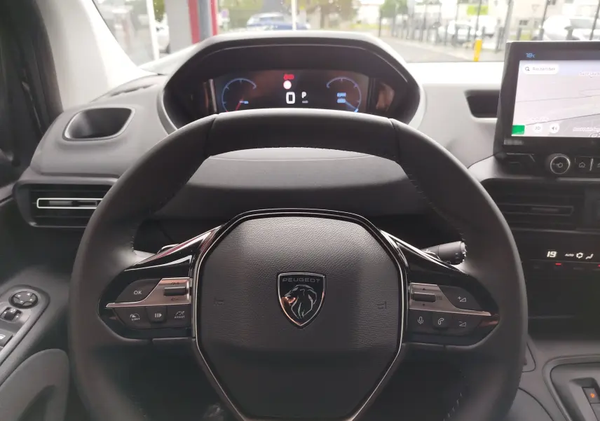 Vue intérieure centrée sur le volant noir du Peugeot Rifter 2026 avec tableau de bord numérique et écran tactile.