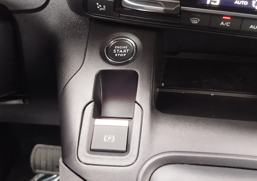 Gros plan intérieur sur le bouton start/stop et la commande de frein à main électronique du Peugeot Rifter noir Perla Nera.