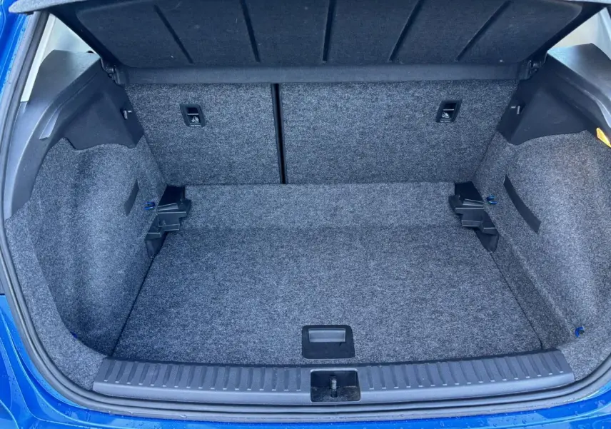 Coffre ouvert vu de l'arrière d'un SEAT Arona bleu saphir avec intérieur de coffre en moquette grise.