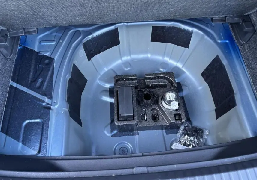 Vue plongeante sur le coffre ouvert du SEAT Arona bleu saphir, montrant le rangement sous plancher sans roue de secours.