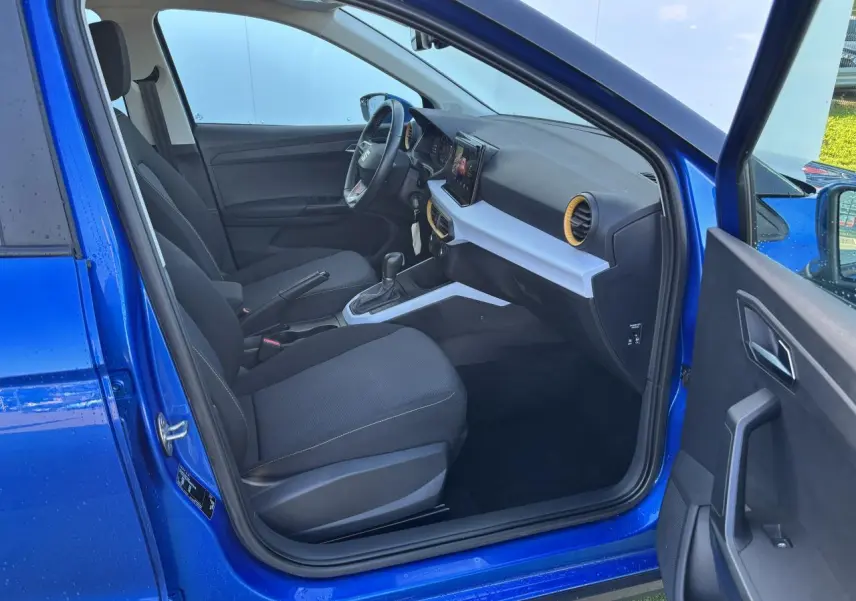 Vue intérieure côté conducteur de la SEAT Arona bleu saphir avec tableau de bord noir et inserts blancs.