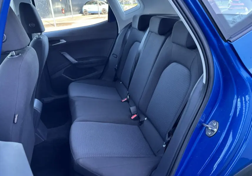Vue intérieure côté droit sur la banquette arrière noire du SEAT Arona bleu saphir avec porte ouverte.