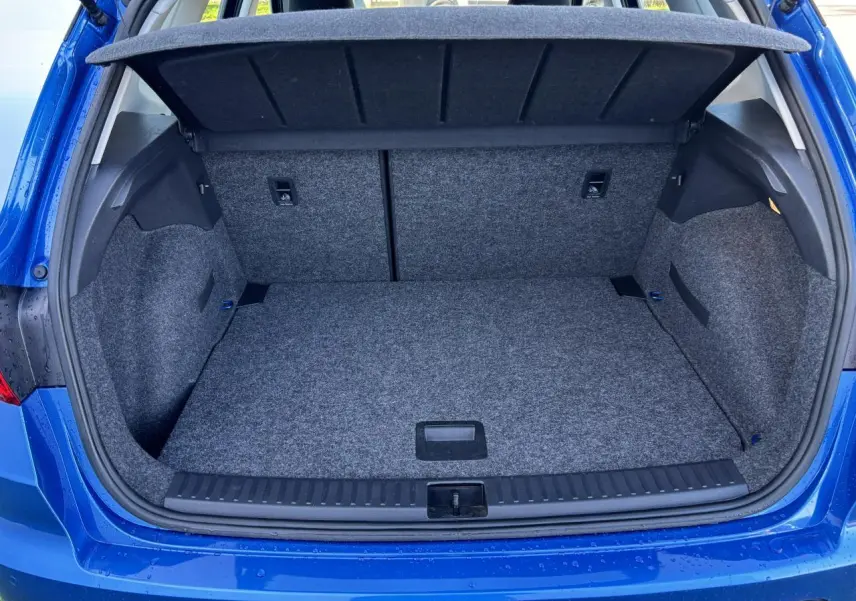 Coffre ouvert vu de l'arrière d'un SEAT Arona bleu saphir avec intérieur gris et cache-bagages relevé.