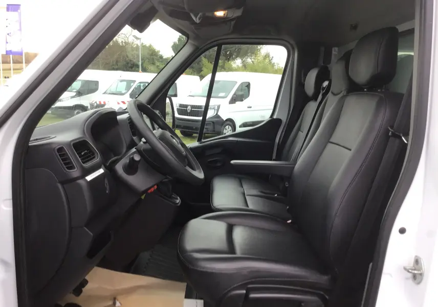 Vue intérieure côté conducteur de l'Opel Movano blanc, montrant les sièges en cuir noir et le tableau de bord.