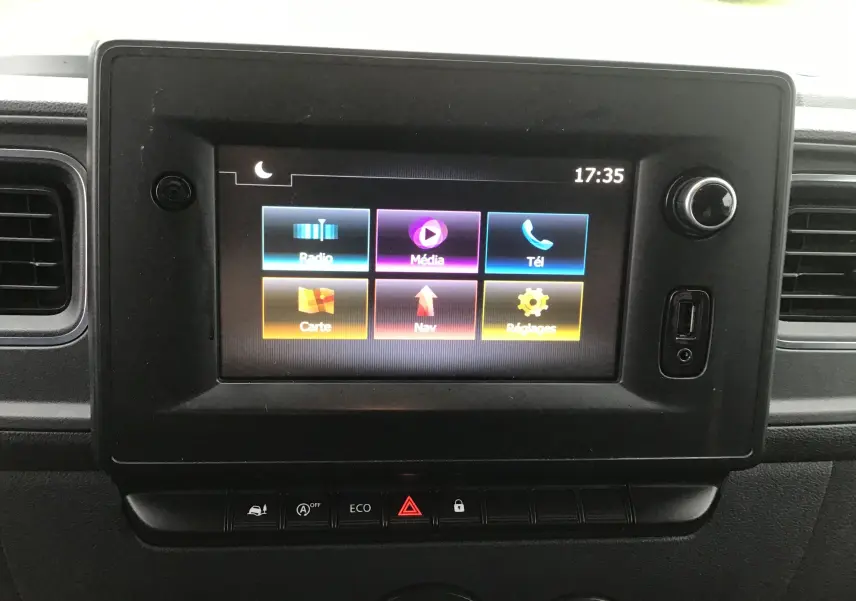 Écran tactile central du tableau de bord de l'Opel Movano blanc, affichant les options multimédia et navigation.