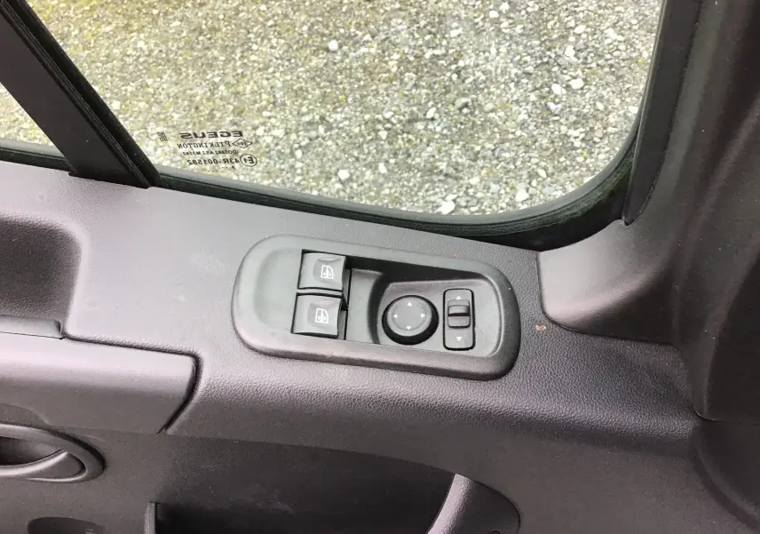 Détail des commandes électriques des vitres et des rétroviseurs sur la porte côté conducteur d’un Opel Movano blanc.