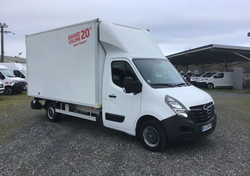 Vue 3/4 avant droite d’un Opel Movano blanc avec caisse volume 20m3 et hayon électrique, sur un parking extérieur.