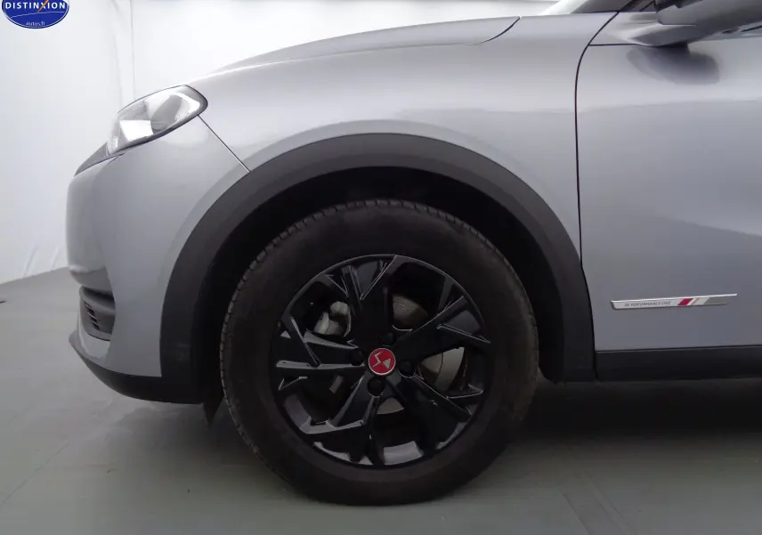 Gros plan sur la roue avant gauche noire et la carrosserie gris Artense d'un DS3 Crossback 1.5BLUEHDI 110 Performance Line.