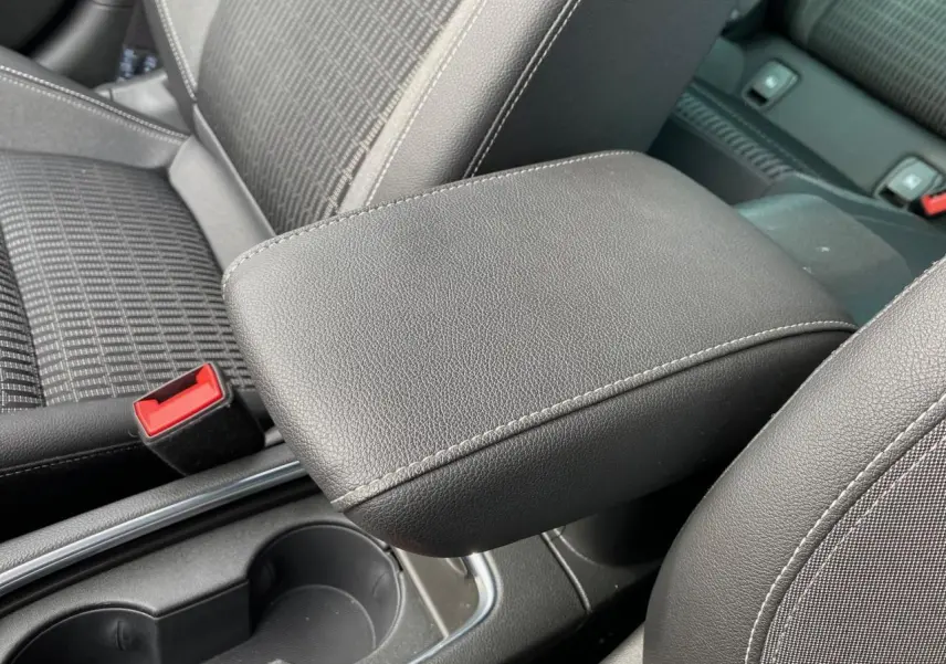 Gros plan sur l'accoudoir central en cuir noir et les sièges tissu gris de l'Opel Astra 2021.