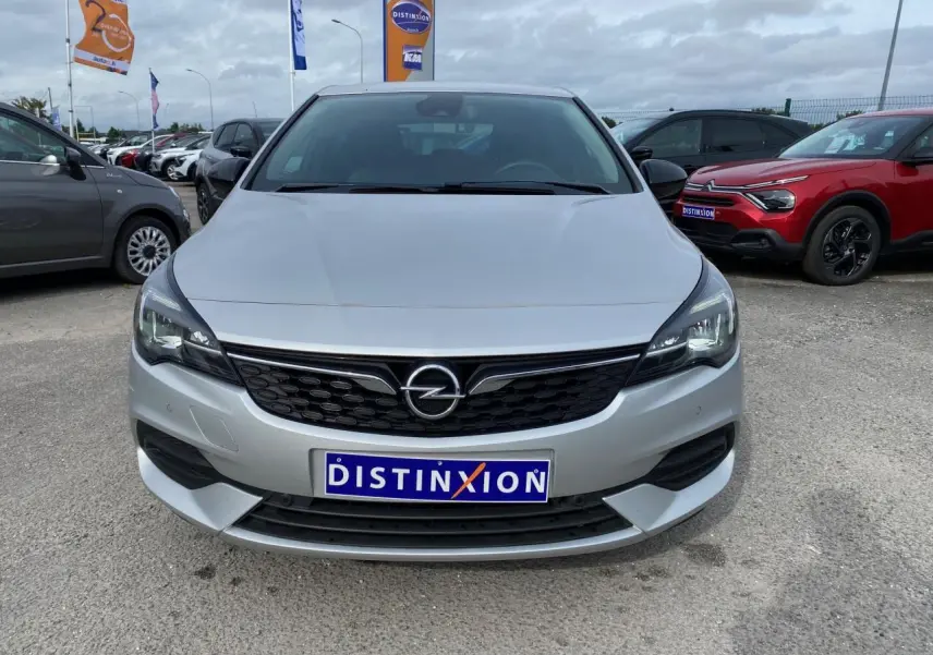 Vue frontale d'une Opel Astra Sovereign Silver 2021 avec calandre noire et phares modernes, stationnée en extérieur.