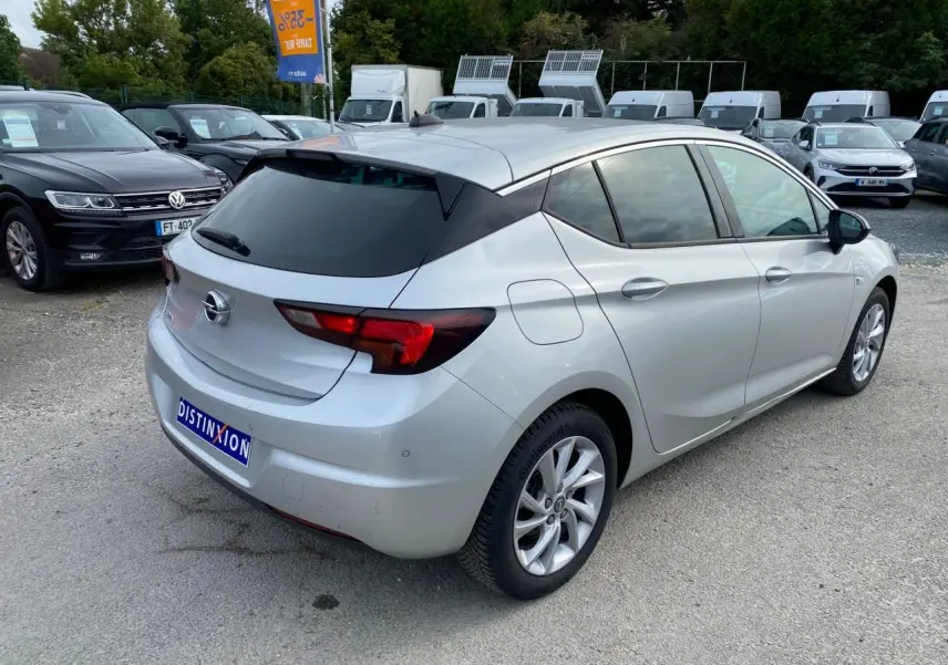 Opel Astra 2021 couleur argent Sovereign Silver vue 3/4 arrière droit avec vitres surteintées et jantes alliage 16 pouces.