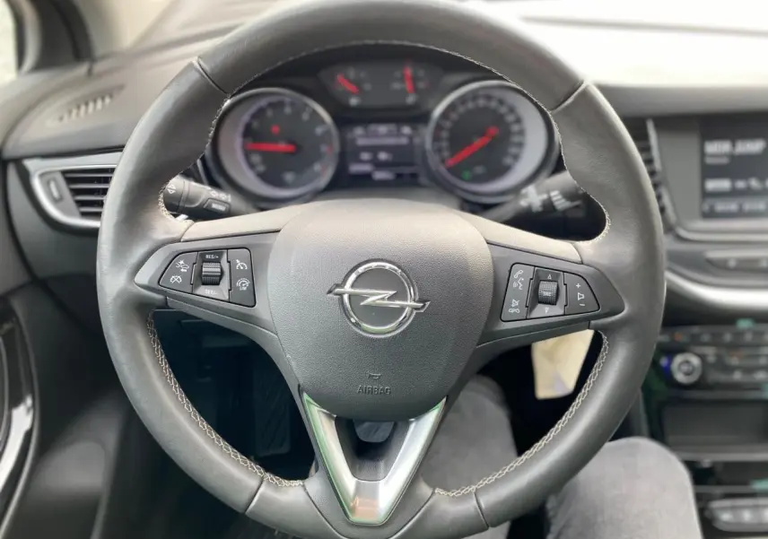 Volant en cuir de l'Opel Astra 2021 vu de face, avec commandes intégrées et tableau de bord en arrière-plan flou.