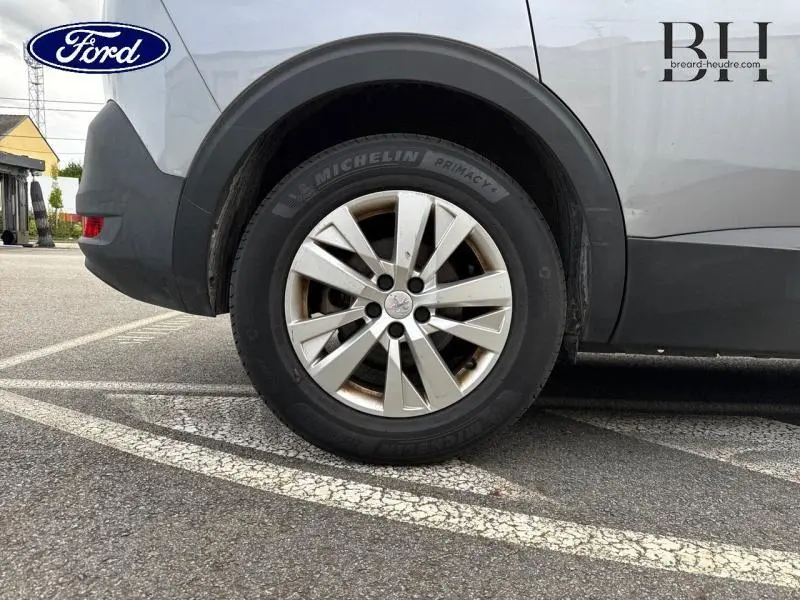 Gros plan sur la roue arrière droite d’un Peugeot 5008 gris Artense avec jante alu et pneu Michelin Primacy.