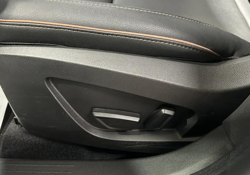 Détail des commandes de réglage électrique du siège conducteur en cuir noir avec surpiqûres marron du Renault Captur II Iconic 2022.