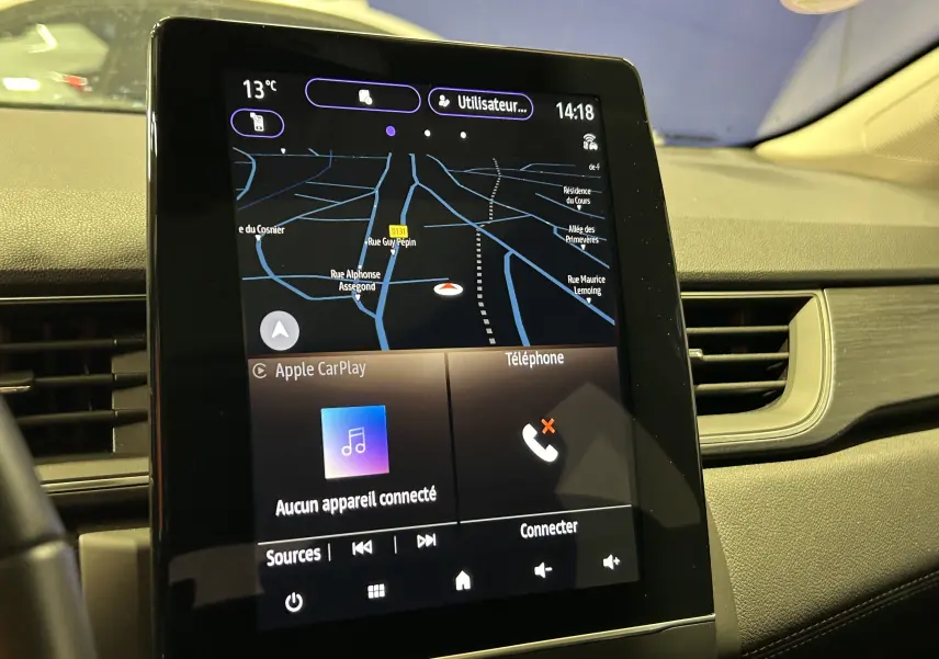 Écran tactile central du tableau de bord du Renault Captur blanc nacré, affichant la navigation et Apple CarPlay.
