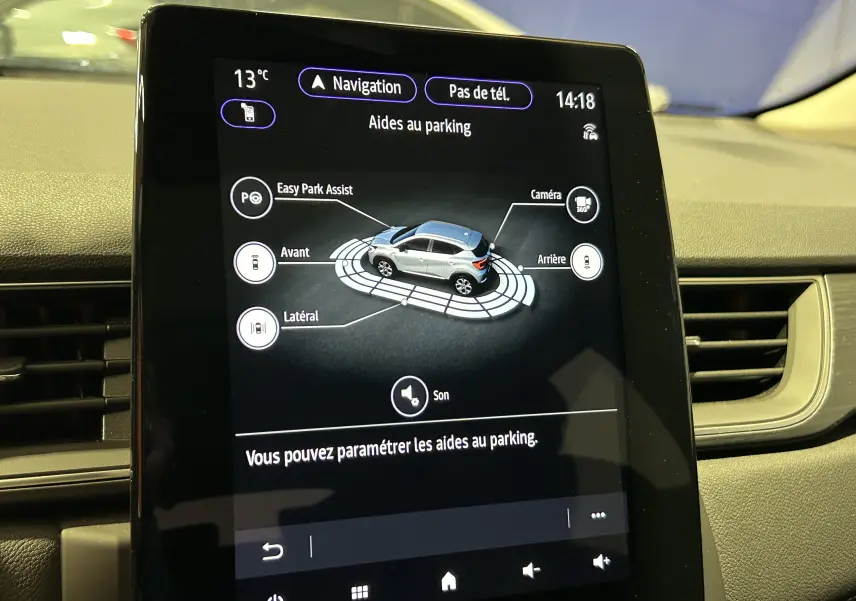 Écran tactile intérieur du Renault Captur blanc nacré de 2022 affichant l'aide au parking avec caméra 360° et capteurs.