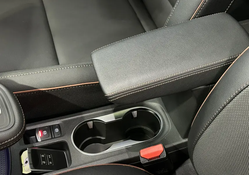 Gros plan de la console centrale noire avec accoudoir et porte-gobelets du Renault Captur II Iconic blanc nacré.