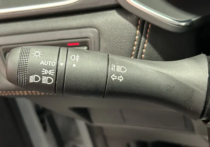 Gros plan sur la commande des phares et clignotants du Renault Captur II Iconic blanc nacré, intérieur cuir noir.