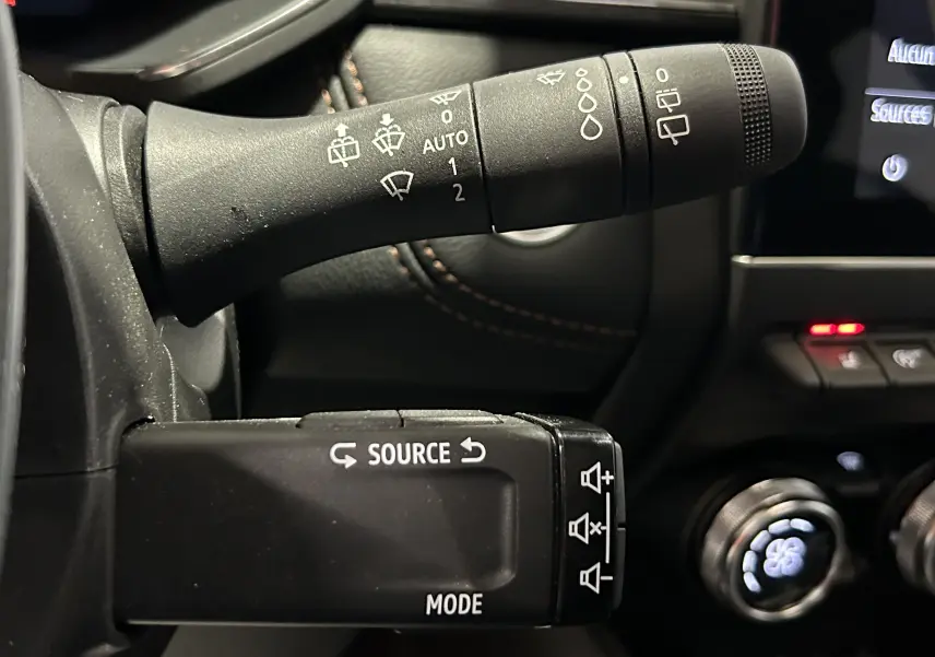 Gros plan sur les commandes au volant du Renault Captur blanc nacré 2022, avec boutons source et mode visibles.