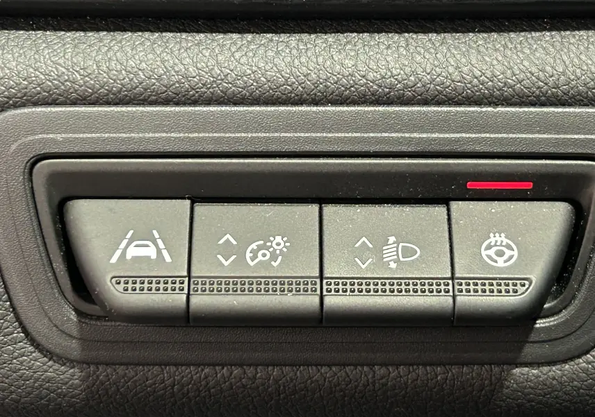 Gros plan sur les boutons de réglage d'assistance et de chauffage du volant dans un Renault Captur II Iconic blanc nacré 2022.