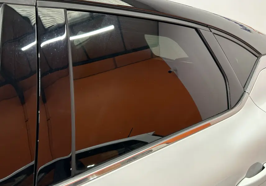 Gros plan sur la vitre arrière côté droit d'un Renault Captur blanc nacré avec cadre de fenêtre noir brillant.