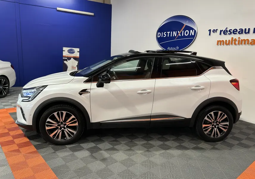 Profil côté gauche d'un Renault Captur blanc nacré 2022 avec toit ouvrant et jantes bi-ton en concession.