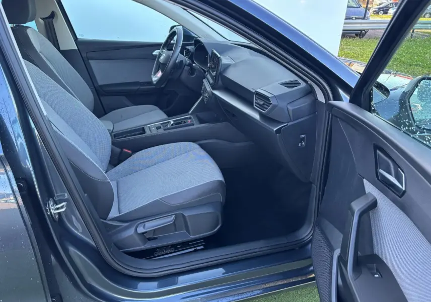 Vue intérieure côté passager avant de la SEAT Leon IV gris magnetic, montrant sièges tissu et tableau de bord moderne.