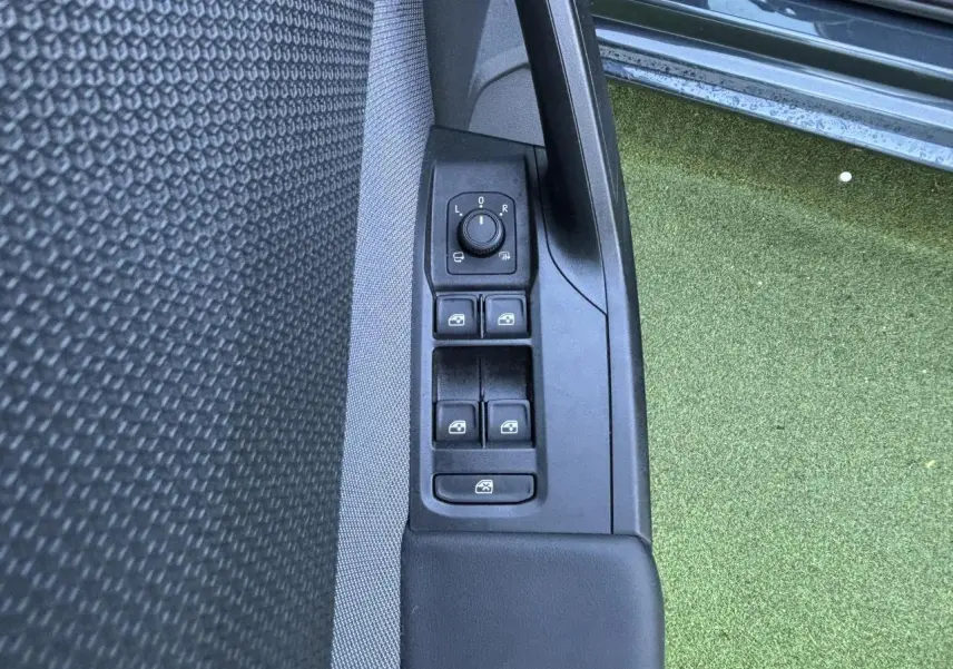 Gros plan sur les commandes des vitres et rétroviseurs côté gauche d'une SEAT Leon IV gris Magnetic, porte ouverte.