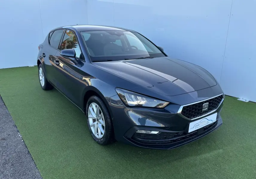 SEAT Leon IV gris magnetic vue 3/4 avant droit sur fond vert avec jantes alliage 16 pouces.