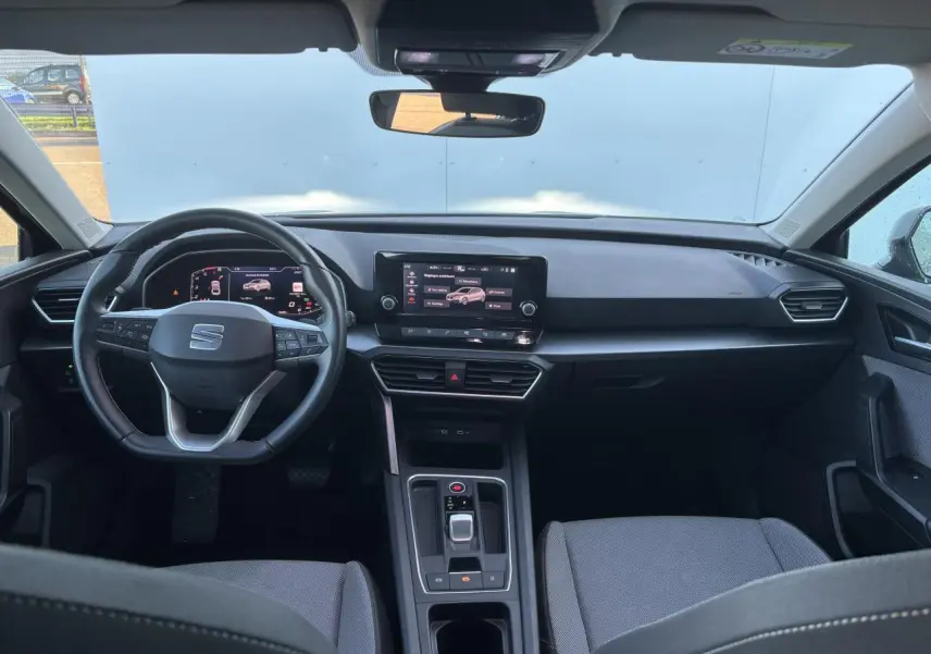 Vue intérieure avant du SEAT Leon IV gris Magnetic, avec tableau de bord digital et écran tactile central.