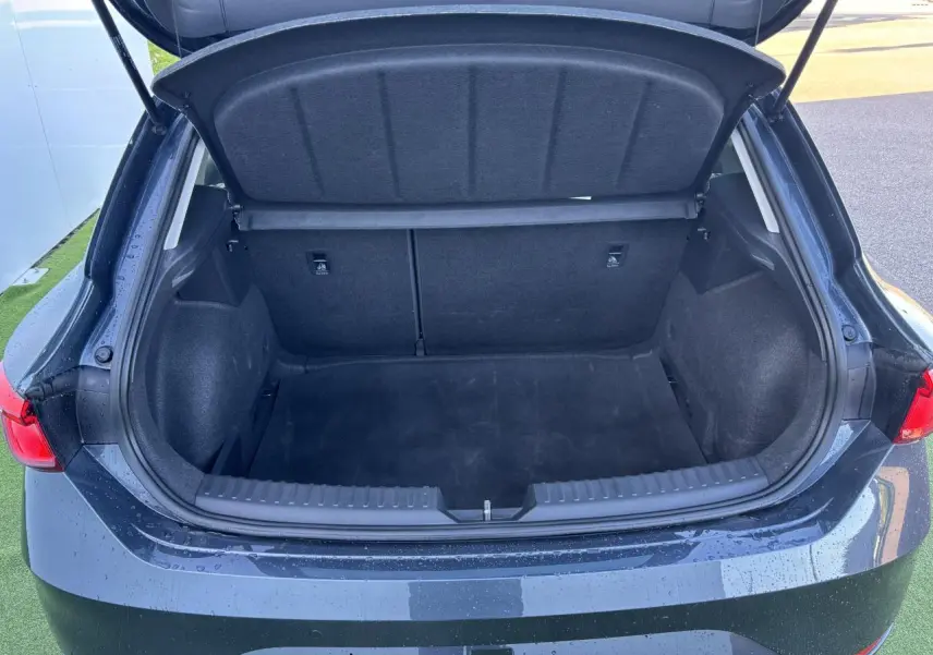 Coffre ouvert vu de l'arrière d'une SEAT LEON IV gris magnetic, montrant un espace de chargement vide et propre.