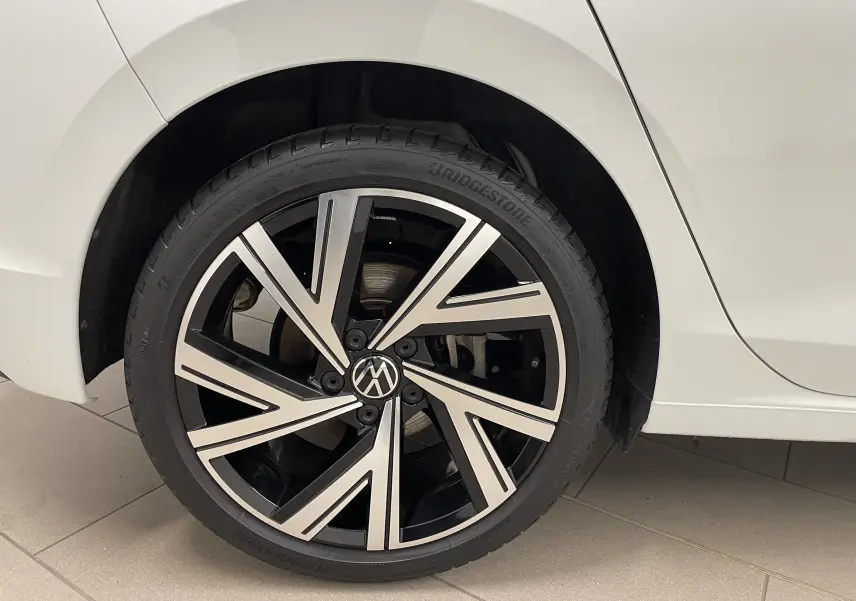 Gros plan sur la roue arrière droite d'une Volkswagen Golf 2023 blanche avec jante alliage Bergamo noire et argent.