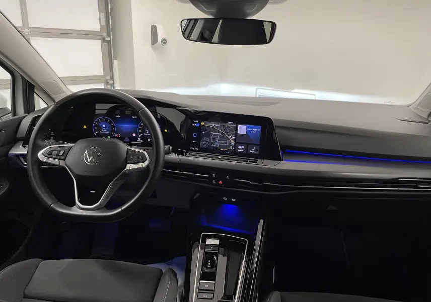Intérieur de la Volkswagen Golf 1.5 eTSI 2023, tableau de bord moderne avec éclairage bleu et écran tactile central.