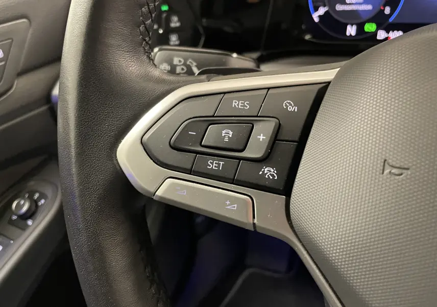 Gros plan sur les commandes de régulateur de vitesse au volant cuir noir de la Volkswagen Golf blanche 2023.